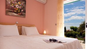 Ein Schlafzimmer mit einem großen Bett, einem Nachttisch und einem Fenster mit Blick auf Grünflächen.