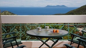 Ein Balkon mit Tisch für zwei Personen, zwei Stühlen und Blick auf Meer und Berge.