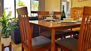 Un coin repas avec une table en bois dressée pour six personnes, entourée de chaises rembourrées.