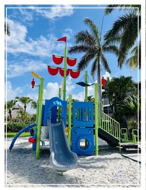 A playground with a slide, climbing structures, and a red flag.