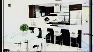 A modern kitchen with dark cabinetry, a built-in oven, and a stainless steel refrigerator. - Refined. Safe. Clean. Waterfront. Golf cart , courtesy to our guests (Key Largo)