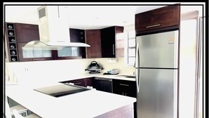 A modern kitchen with a stainless steel refrigerator, a built-in oven, and dark wooden cabinets. - Refined. Safe. Clean. Waterfront. Golf cart , courtesy to our guests (Key Largo)