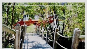 A wooden bridge with a rope barrier, leading to a building with a red staircase. - Refined. Safe. Clean. Waterfront. Golf cart , courtesy to our guests (Key Largo)