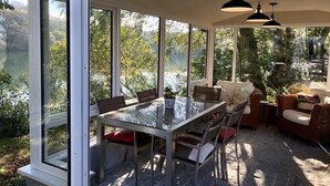 A sunroom with a glass table and chairs, a sofa, and wicker furniture. - Cosy  barn close to Praa Sands (Helston)
