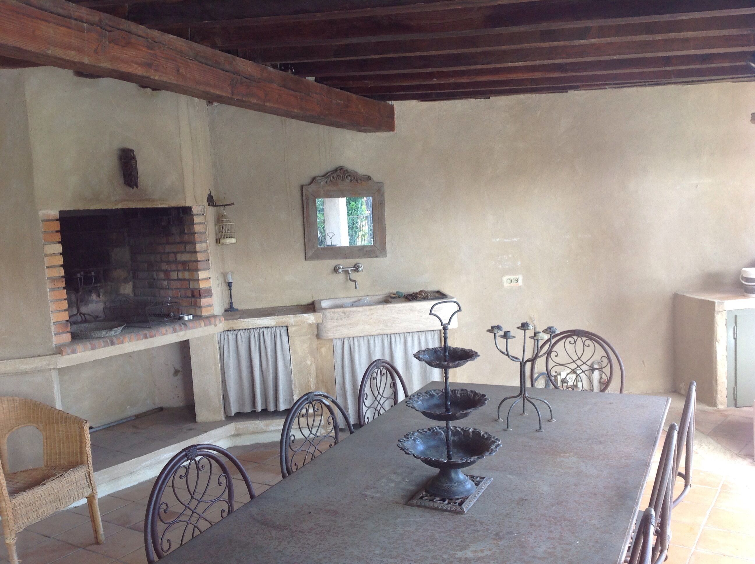 A rustic outdoor dining area with a brick oven, a sink, and a mirror above it.