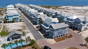 Un quartier résidentiel situé sur la côte, avec de nombreuses maisons à deux étages, une piscine et une plage en arrière-plan.