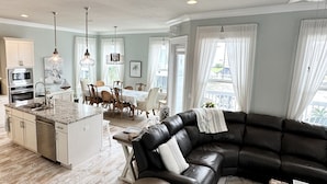 Une cuisine moderne avec un îlot central, un coin repas comprenant une table et des chaises, un canapé en cuir noir et une petite table ronde.