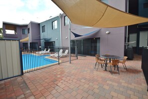 Relax by the pool under a shaded canopy, surrounded by a beautifully paved patio.