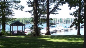 A gazebo in a park with a lake and boats in the background.