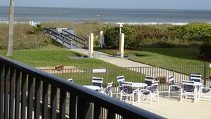 A patio with outdoor seating, a staircase leading to a deck, and a view of the ocean. - BEACHSIDE Paradise: 3BR Condo with Heated Pool - Steps to Cocoa Beach Pier! (Cocoa Beach)