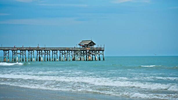 A pier extending into the sea with a small building at the end. - BEACHSIDE Paradise: 3BR Condo with Heated Pool - Steps to Cocoa Beach Pier! (Cocoa Beach)