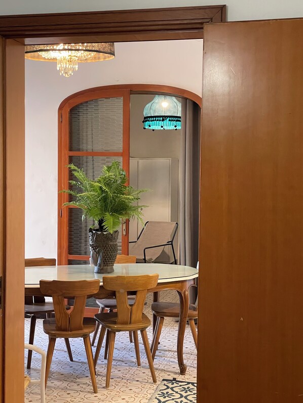 A dining area with a round table, wooden chairs, a potted plant, and a chandelier.