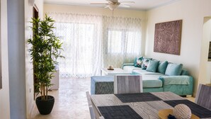 A living room with a sofa, a coffee table, and a potted plant. - Beautiful 2 bedroom 2 bath in a beachfront community (Punta Cana)