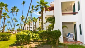 A modern hotel with a balcony, palm trees, and a well-maintained garden. - Beautiful 2 bedroom 2 bath in a beachfront community (Punta Cana)