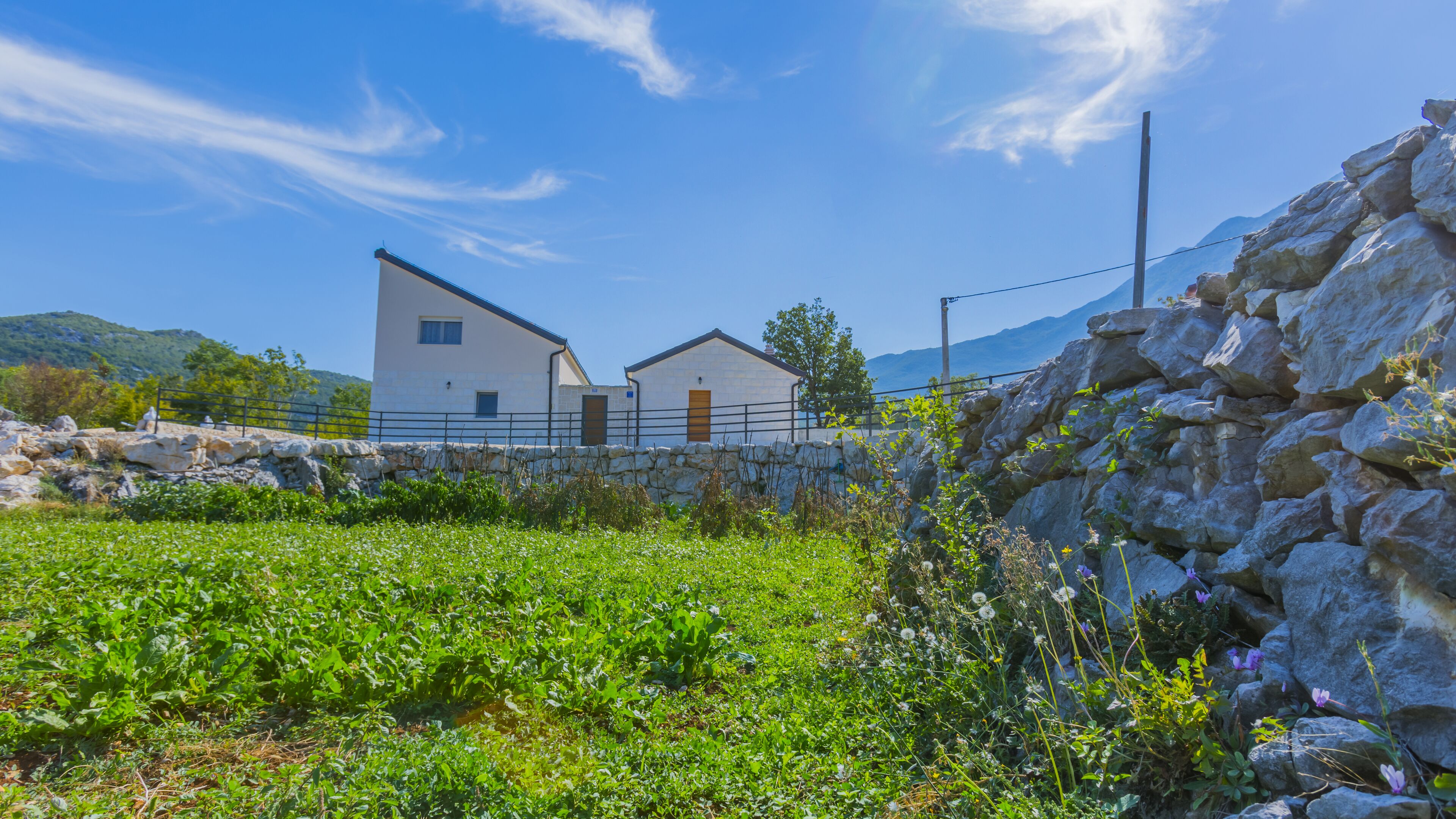 A white building with a stone wall and a stone fence.