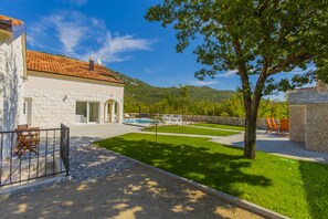 A villa with a swimming pool, outdoor seating, and a view of the mountains.