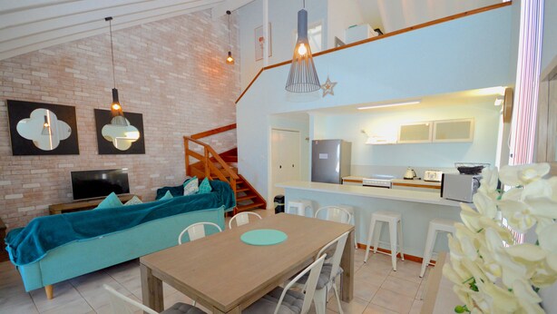Uma sala de estar moderna com sofá, mesa de jantar e cozinha.