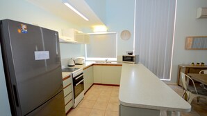 Uma cozinha compacta com geladeira, forno, pia e área de refeições com mesa e cadeiras.