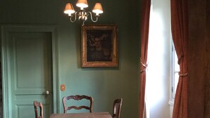 A dining room with a wooden table, chairs, a chandelier, and a painting on the wall.