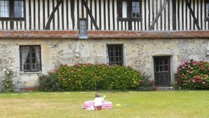 A traditional half-timbered building with stone walls and a grassy lawn in front.