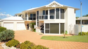 Une maison à deux étages avec un garage, comprenant deux logements numérotés 1 et 2, et une pelouse bien entretenue.