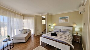Une chambre à coucher avec un lit, un canapé, une table de chevet, une lampe et une fenêtre avec des rideaux.