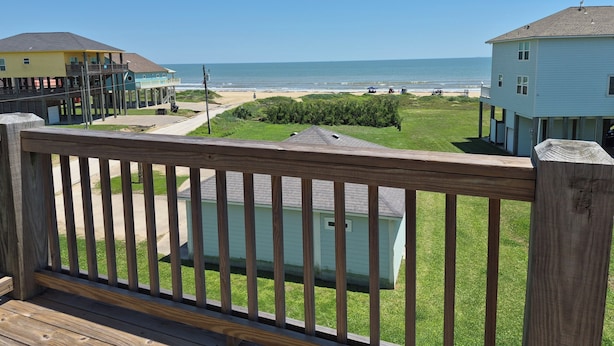 Eine Holzterrasse mit Blick auf eine Wohngegend und den Strand.
