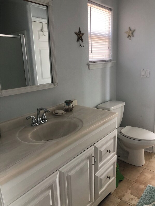 A bathroom with a sink, mirror, toilet, and decorative starfish on the wall. - Stunning Beachfront Home with Panoramic Views & Family-Friendly Charm (Bolivar Peninsula)