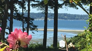 A garden with a wooden fence, a sign for Stone Cottage, and a view of a lake with boats.