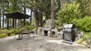 An outdoor patio with a stone fireplace, a grill, and patio furniture.