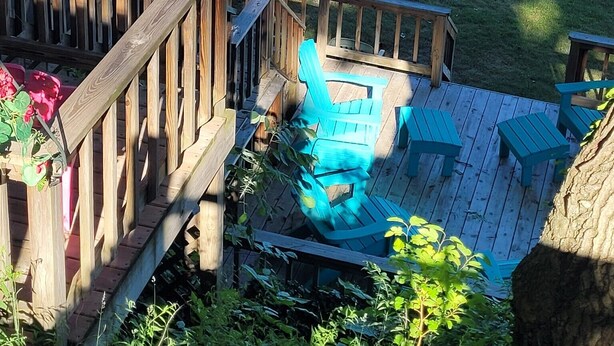 Una terraza de madera con un muelle para barcos, un árbol y una zona cubierta de césped.