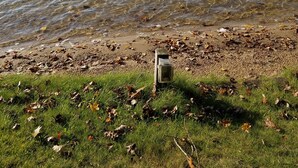 Un lago con un muelle y una bandera amarilla.