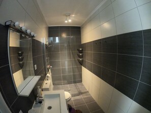 A modern bathroom with a large mirror, a sink, and a shower area. - Spring Apartment (Costa del Silencio)
