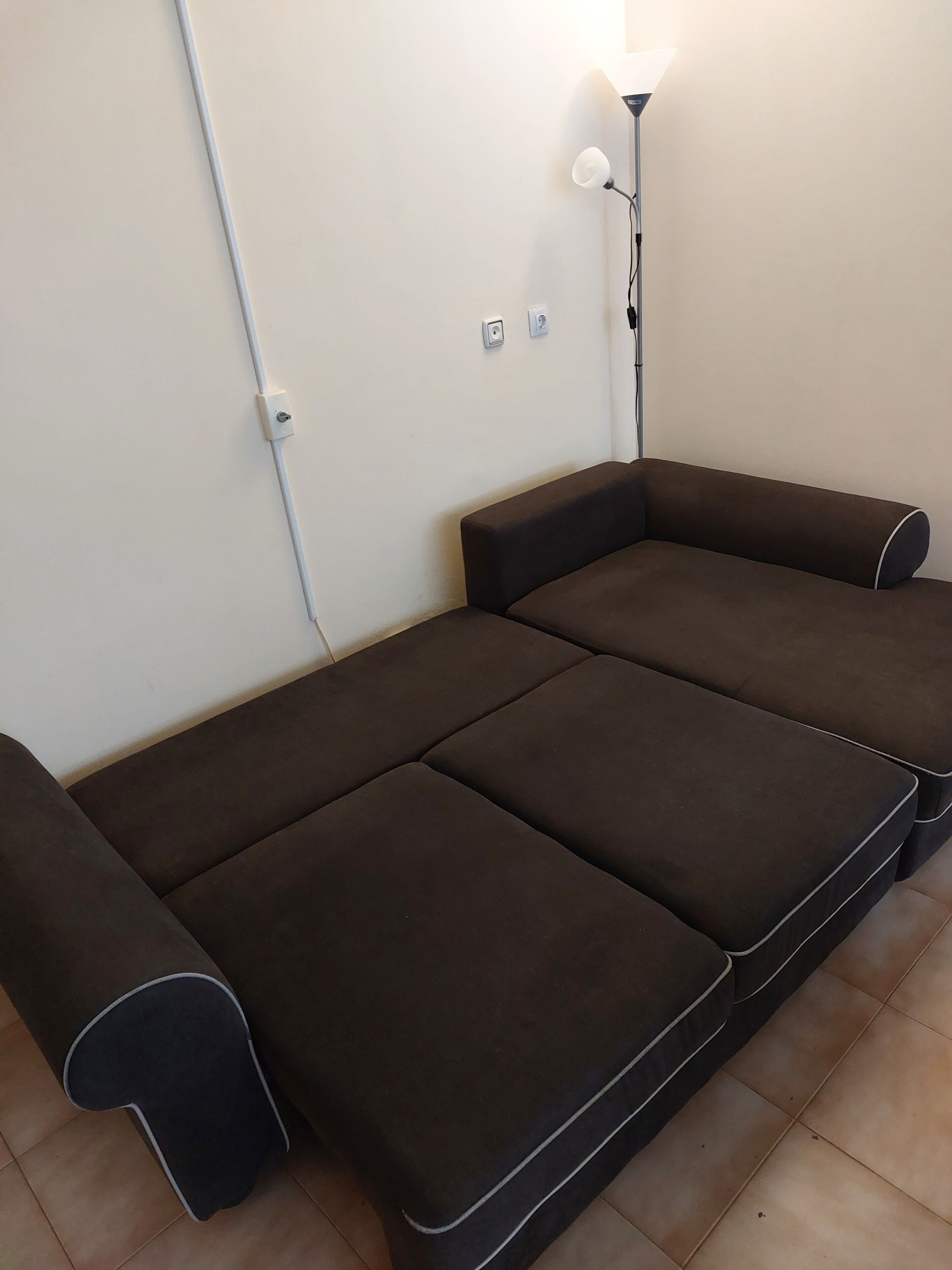 Un sofá marrón con una lámpara en la pared.