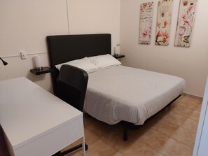 A single bed with a black headboard, a bedside table with a lamp, and a white desk. - Spring Apartment (Costa del Silencio)