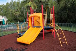 A playground with a yellow slide and red and yellow play structures. - Cozy Home Away From Home - VB010 (Kissimmee)