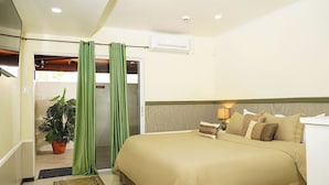A hotel room with a bed, a nightstand, a lamp, a potted plant, and a sliding door.