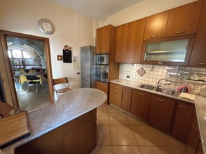 A kitchen with wooden cabinets, a stainless steel sink, and a refrigerator.