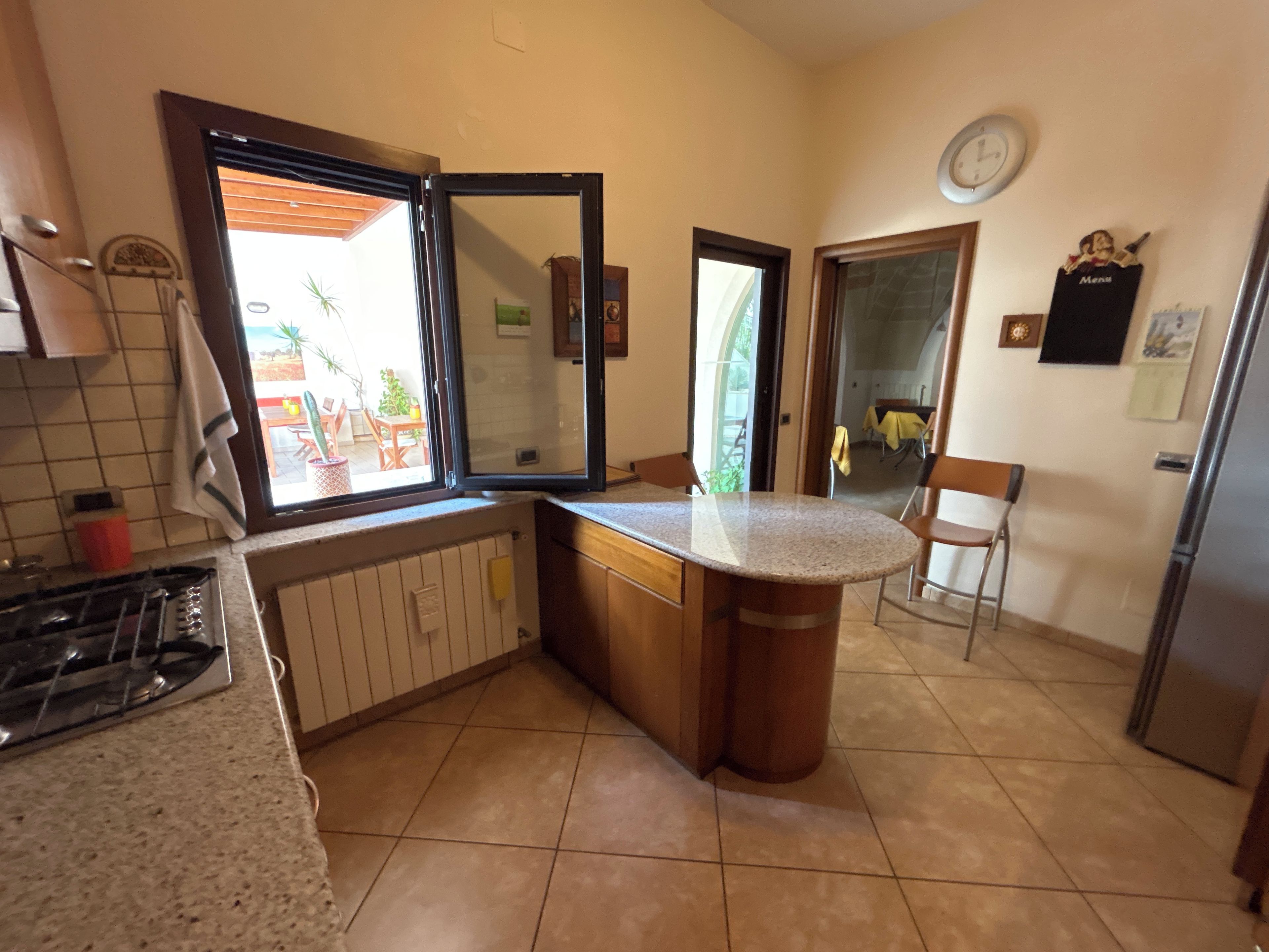 A kitchen with a gas stove, a sink, a window, and a door leading to a patio.