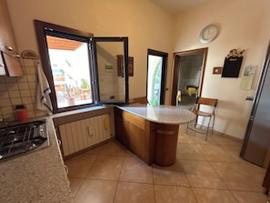 A kitchen with a gas stove, a sink, a window, and a door leading to a patio. - Villa in Lecce (Lecce)
