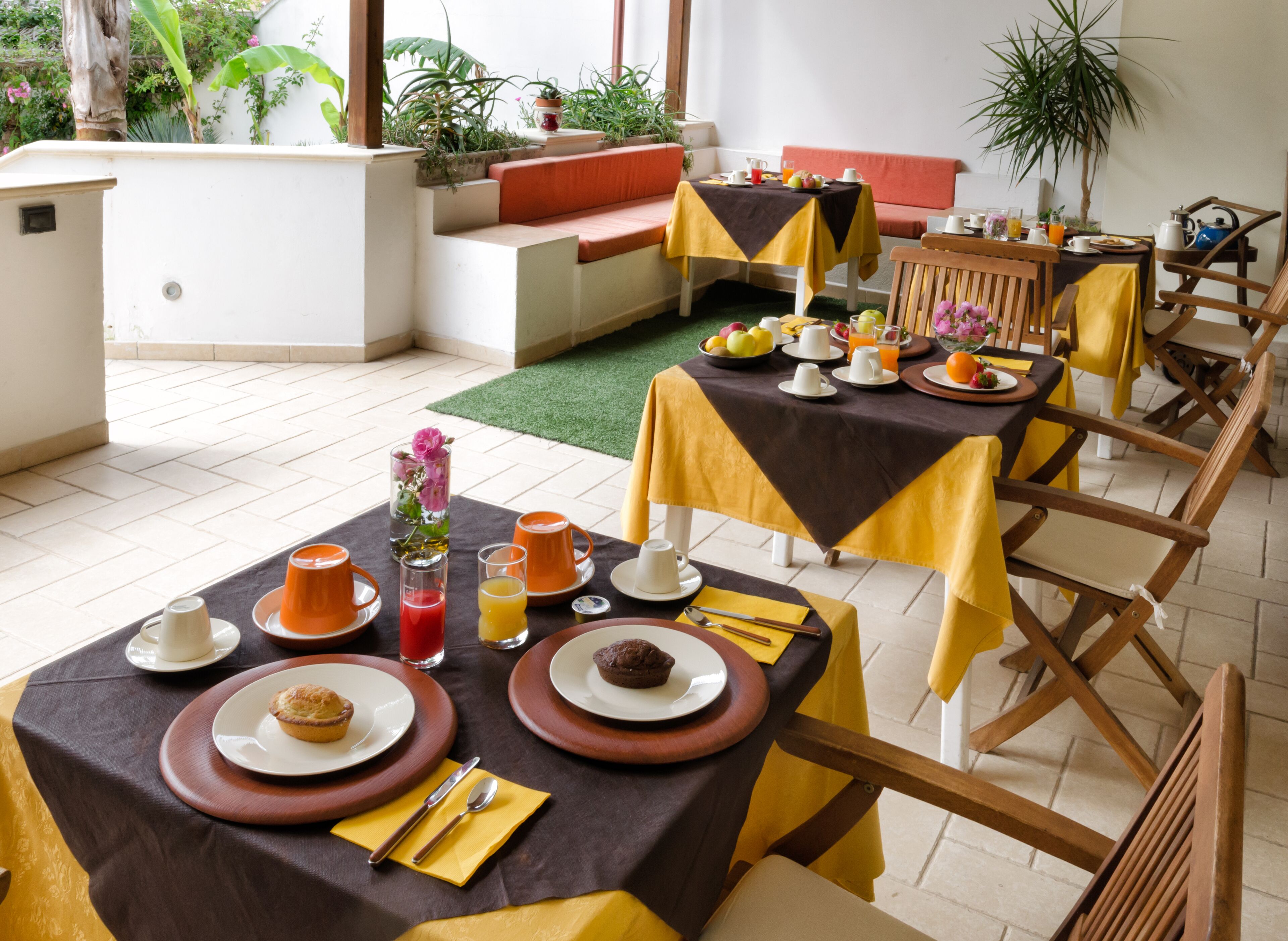 Una disposición para el desayuno con mesas, sillas y una variedad de alimentos y bebidas.