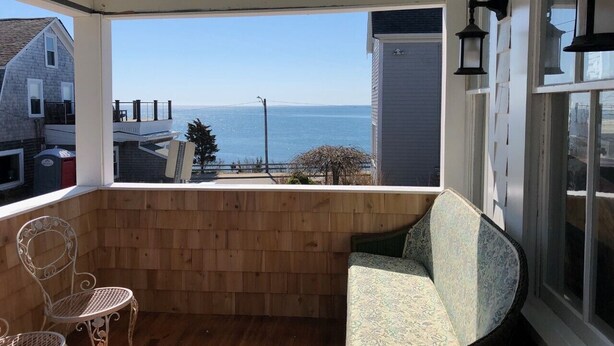Un pontile in legno con vista sull'oceano, una sedia e una lampada.