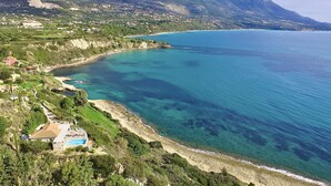 Un paysage côtier offrant une vue dégagée sur la mer, une plage et un arrière-plan montagneux.