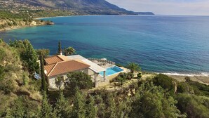Une propriété située sur la côte, dotée d’une piscine et entourée de verdure et de montagnes.