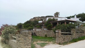 A stone-walled property with a staircase leading to a white building, surrounded by greenery and a view of a rocky hill. -  House with sea views. Free WIFI. Punta Paloma, Tarifa (Tarifa)