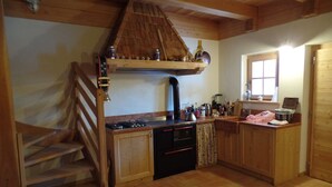 A kitchen with wooden cabinets, a stove, a sink, and a window. - MASET POZZATTI MOUNTAIN CHALET (Baselga)