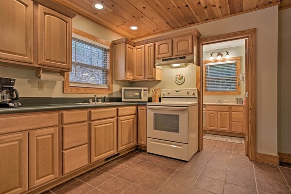 Enjoy cooking in this well-lit kitchen with a stainless steel range hood, microwave, large sink, and oven.