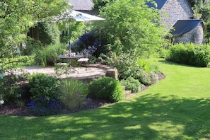 A garden with a stone table and chairs, surrounded by various plants and flowers.