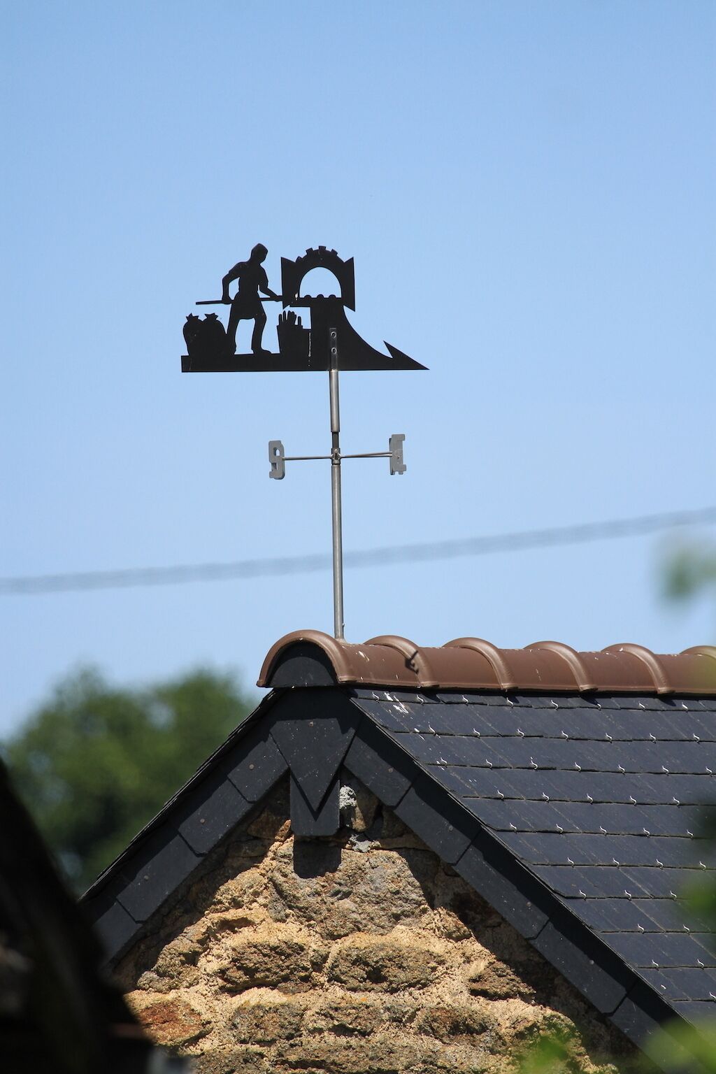 A weather vane with a silhouette of a farmer and a cow on a roof.