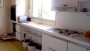 Une cuisine équipée d’une cuisinière à gaz, d’une fenêtre et d’un plan de travail sur lequel se trouve une radio.